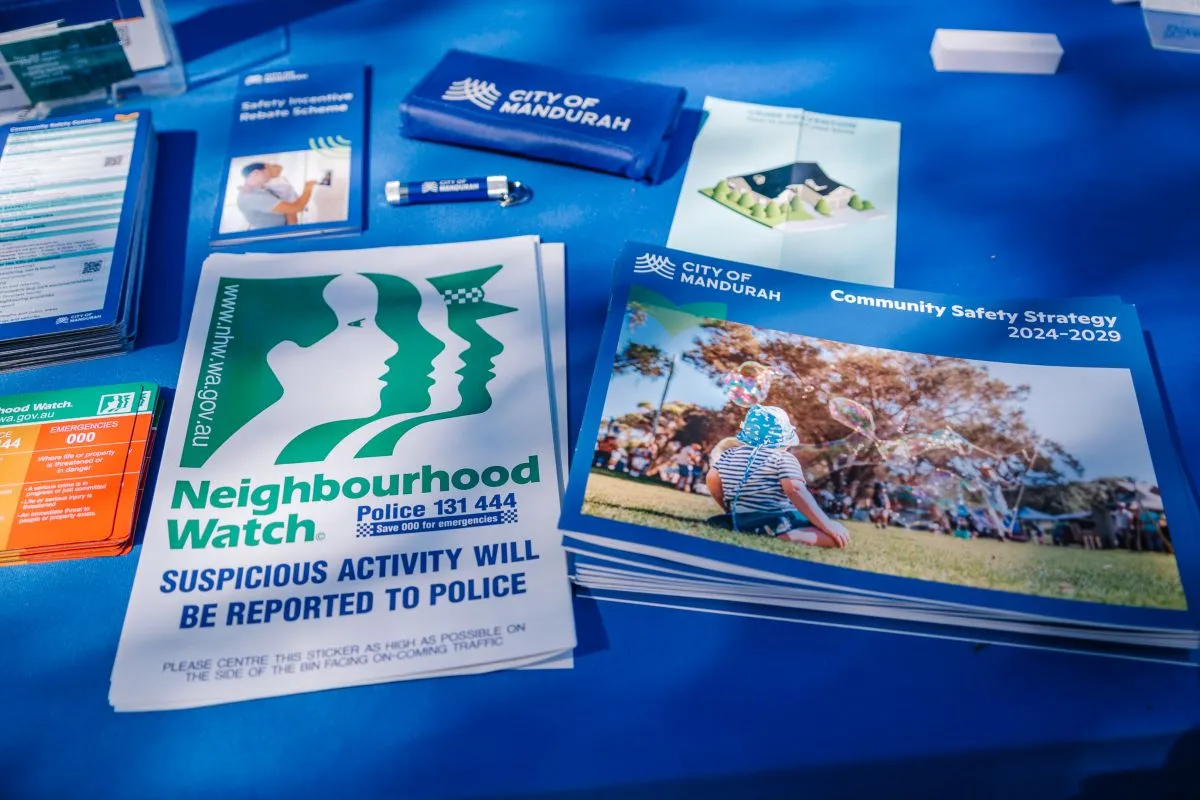 Printed Neighbourhood Watch and Community Safety Strategy materials displayed on a table at a community event